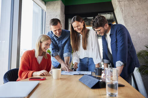 Lächelnde Geschäftsleute, die im Büro über Daten diskutieren - BSZF02393