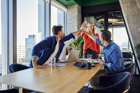 Happy business people giving high-five to each other in office - BSZF02418