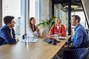 Happy businessmen and businesswomen discussing in office meeting - BSZF02419