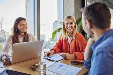 Glückliche Geschäftsleute und Geschäftsfrauen bei einer Diskussion im Büro - BSZF02421