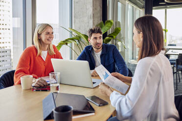 Young businessman discussing with colleagues over data in office - BSZF02429