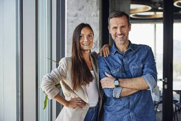 Happy businesswoman standing with colleague in office - BSZF02473