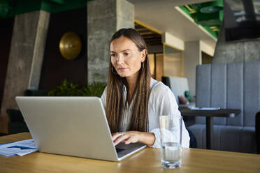 Geschäftsfrau arbeitet am Laptop im Büro - BSZF02504