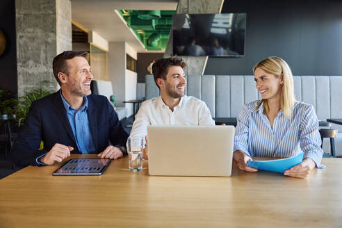 Smiling business people having meeting at desk in office - BSZF02521