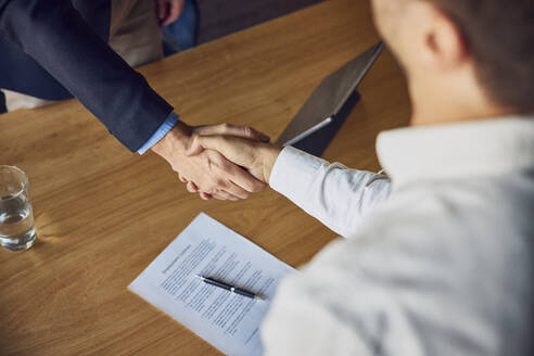 Recruiter shaking hands with candidate at desk - BSZF02543