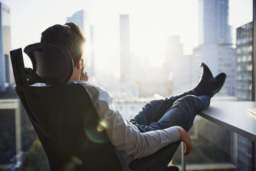 Nachdenklicher Geschäftsmann sitzt auf einem Bürostuhl und schaut durch ein Fenster - BSZF02608