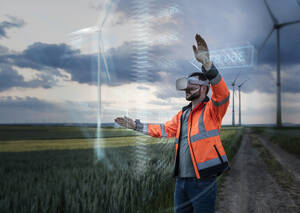 Engineer wearing VR glasses and programming through digital wind turbine design in field - UUF31005