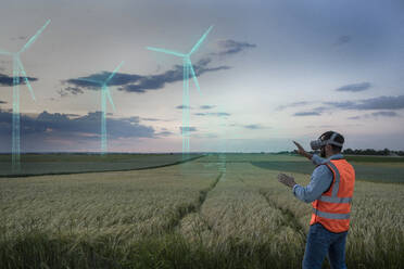 Engineer looking at digital wind turbine models in field - UUF31006