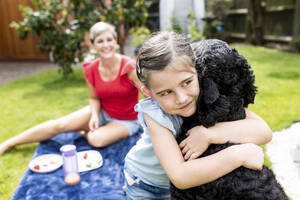 Nachdenkliches Mädchen umarmt Hund im Garten - WPEF08152