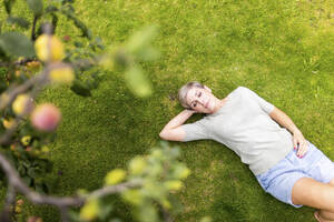 Frau liegend auf Gras im Garten - WPEF08163