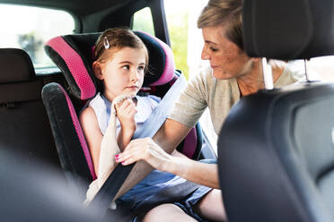 Mother helping daughter to fasten seat belt in car - WPEF08168