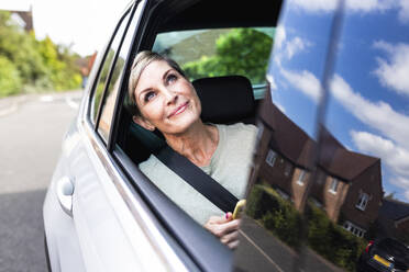 Lächelnde Frau träumt im Auto sitzend - WPEF08173