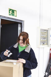 Happy delivery woman stamping package document at distribution warehouse - PCLF00974