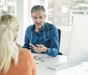 Doctor gesturing and talking to patient in clinic - UUF31021