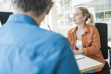 Young businesswoman having discussion with colleague in office - UUF31031