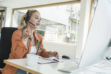 Doctor wearing headset and talking on video call in clinic - UUF31039