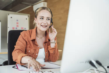 Smiling businesswoman wearing headset and having video conference - UUF31040