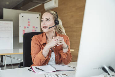 Smiling businesswoman wearing microphone headset in office - UUF31042