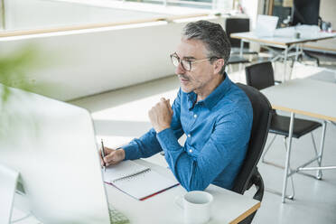 Reifer Geschäftsmann mit Computer am Schreibtisch - UUF31050