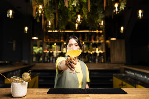 Barkeeper gibt Cocktailglas an der Bar - DAMF01283