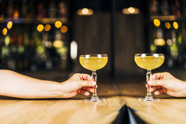 Woman with cocktail drink on table near mirror in bar - DAMF01284