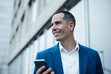 Smiling businessman with mobile phone - JOSEF23058