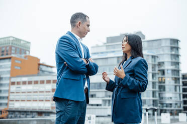 Businesswoman discussing with colleague in front of buildings - JOSEF23067