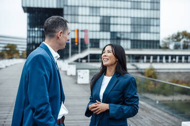 Smiling businesswoman talking to colleague in office park - JOSEF23068