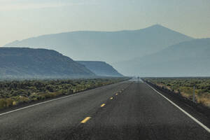 Leere Autobahn, die durch die Wüste führt, mit Bergen im Hintergrund - TETF02396