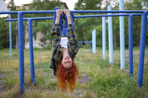 Redhaired woman hanging on bars at playground - TETF02450