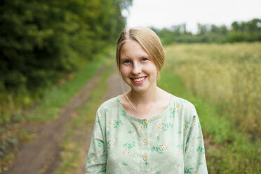 Portrait of smiling woman standing in field - TETF02457