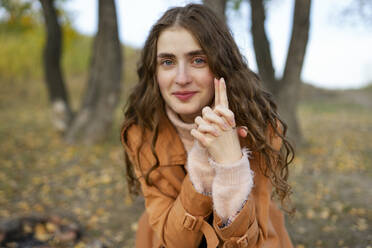 Portrait of smiling woman with hands clasped in park - TETF02505