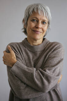 Lächelnde Frau mit Pullover vor grauem Hintergrund - EBSF04340