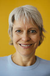 Smiling woman against yellow background - EBSF04347