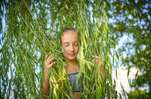 Girl with eyes closed holding leaves of willow tree - DIKF00806