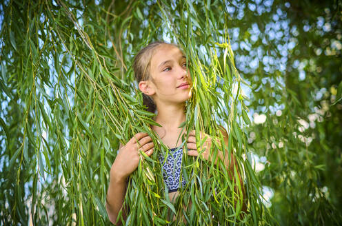 Mädchen hält Blätter eines Weidenbaums - DIKF00808