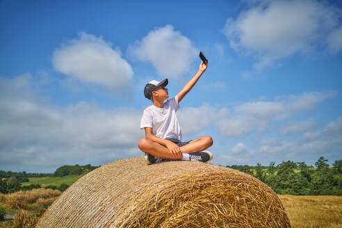 Teenager, der ein Selfie mit seinem Smartphone an einem sonnigen Tag macht - DIKF00816