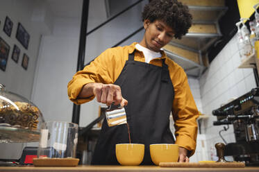 Junge Barista gießt Kaffee in eine Tasse im Café - ALKF00945