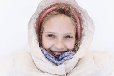 Lächelndes Mädchen mit warmer Kleidung im Schnee - EYAF02908