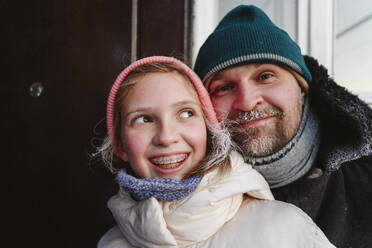 Lächelndes Mädchen mit Vater in warmer Kleidung zu Hause - EYAF02909