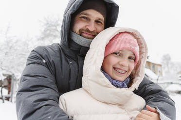 Smiling father embracing daughter in winter - EYAF02910
