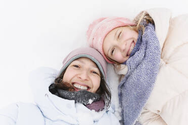 Glückliche Mutter und Tochter im Schnee liegend im Winter - EYAF02918