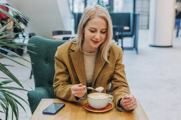 Smiling woman with blond hair having coffee in cafe - VSNF01559