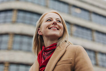 Happy woman wearing red bandana in front of building - VSNF01578