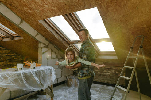 Vater mit Tochter, die sich auf dem renovierten Dachboden vergnügen - YTF01600