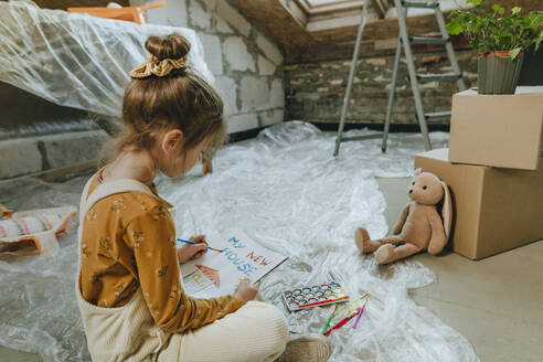 Mädchen malt Haus Zeichnung auf Buch sitzen mit Teddybär zu Hause - YTF01610