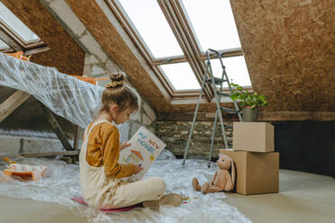Girl painting in book sitting near skylight window at home - YTF01612