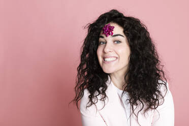 Glückliche junge Frau mit gebundener Schleife auf der Stirn vor rosa Hintergrund - LMCF00834
