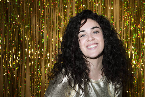 Happy young woman in front of tinsel curtain - LMCF00838