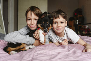 Brüder liegen mit Hund auf dem Bett - EYAF02919